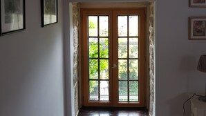 A hallway with a wooden door leading to an outdoor area, framed pictures on the walls, and a lamp on the right. - Beautifully Restored Detached Stone House (Jugon-Les-Lacs - Commune Nouvelle)
