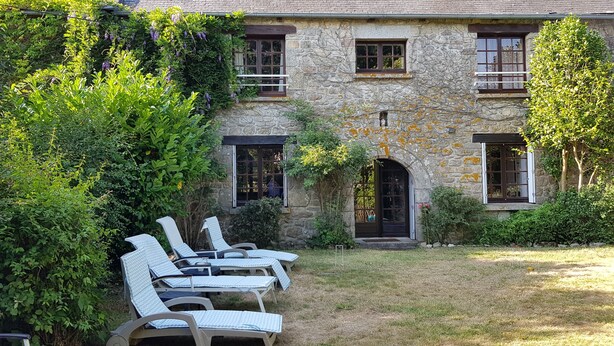 A stone building with a garden and outdoor seating area. - Beautifully Restored Detached Stone House (Jugon-Les-Lacs - Commune Nouvelle)