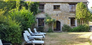 A stone building with a garden and outdoor seating area. - Beautifully Restored Detached Stone House (Jugon-Les-Lacs - Commune Nouvelle)