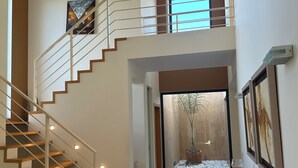 A modern interior with a wooden staircase, a glass door leading to a garden, and framed artwork on the walls. - Amazing Villa - Lagos (Lagos)