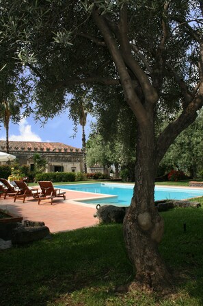 A pool area with lounge chairs, a tree, and a building in the background. - Historical country house near Taormina & the sea. Stunning view of Mt Etna (Taormina)