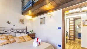 A bedroom with a bed, pillows, a nightstand, and a wooden ceiling. - Studio Cavour (alghero)