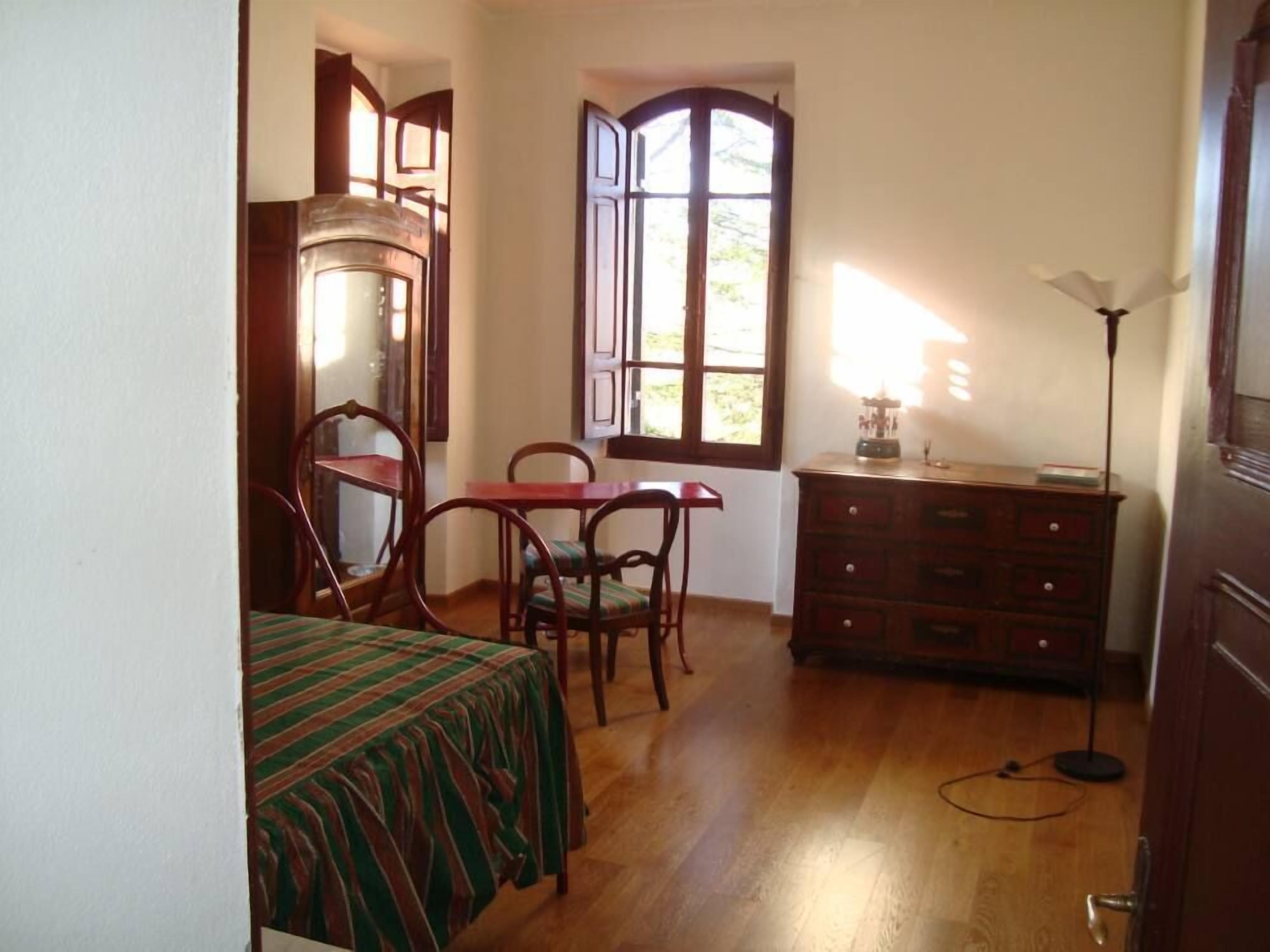 Una habitación con cama, escritorio, silla, cómoda y ventana con cortinas.