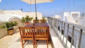 A rooftop terrace with a wooden table and chairs, potted plants, and a large umbrella. - CASA ROMA HISTORIC CENTER WIFI (Ostuni)