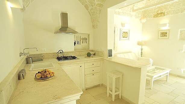A kitchen with a stone arch, white cabinetry, a gas stove, and a countertop with a bowl of fruit. - CASA ROMA HISTORIC CENTER WIFI (Ostuni)
