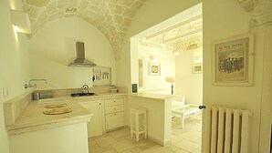 A kitchen with white cabinets, a stone arch, a gas stove, and a radiator. - CASA ROMA HISTORIC CENTER WIFI (Ostuni)