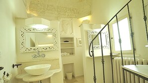 A bathroom with a white sink, ornate mirror, and a staircase with a metal railing. - CASA ROMA HISTORIC CENTER WIFI (Ostuni)