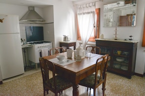 A compact kitchen with a stove, oven, and refrigerator. There is a dining table with chairs and a cabinet with glass doors. - New Central, Cozy, 2 bedrooms, living room, free wifi, AC, 51 inch LED TV (Venezia)