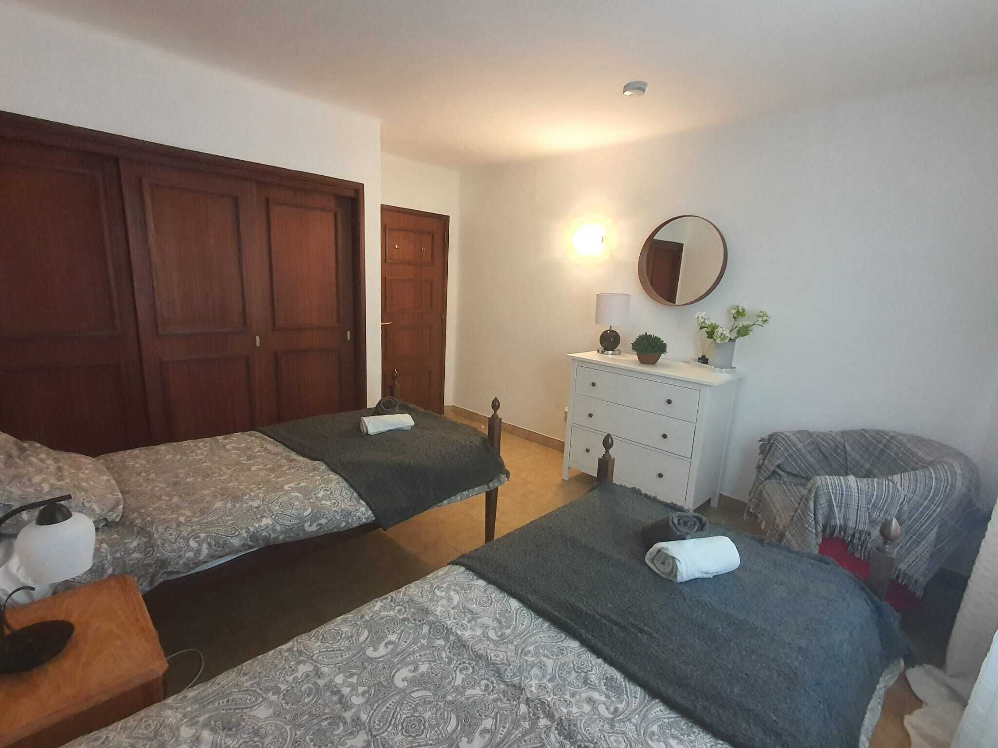 Un dormitorio con dos camas, un tocador, un espejo y una lámpara.