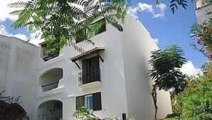 A multi-story building with a white facade, balconies, and a staircase leading to the entrance. - Spacious, well equipped apartment, broadband, Sky TV, with pool just outside. (Albufeira)