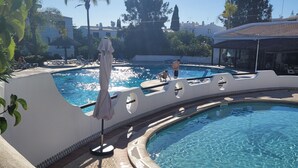 A swimming pool with lounge chairs and a covered seating area. - Spacious, well equipped apartment, broadband, Sky TV, with pool just outside. (Albufeira)