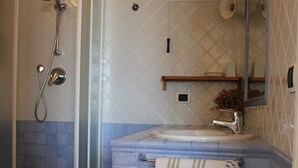 Un baño con ducha de vidrio, un lavamanos con toalla y un espejo.