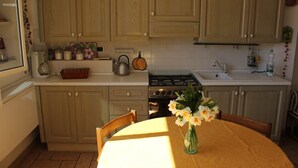 Una cocina con armarios de madera, estufa, lavabo y una mesa de comedor con sillas.