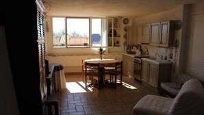 Una cocina con una mesa de comedor, sillas y una ventana. Hay un sofá en la esquina.