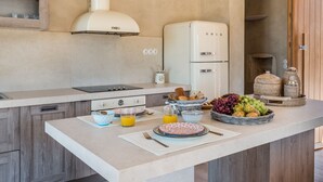 A modern kitchen with a central island, a built-in oven, and a hanging light fixture. - The Old Beach House - A house by the sea to reconnect with yourself (Keramoti western crete)