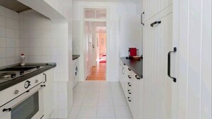 Une cuisine étroite avec des meubles blancs, une cuisinière et un plan de travail.