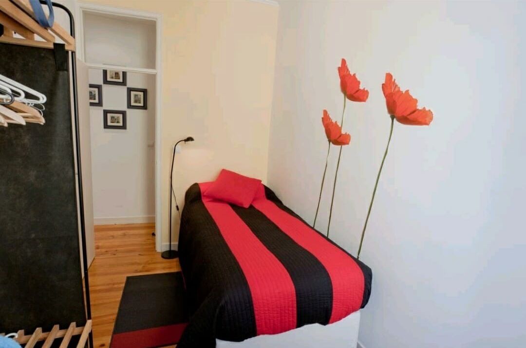 Un dormitorio con cama, armario y estante de pared con fotografías.