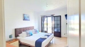 Un dormitorio ordenado con cama, mesita de noche y ventana con cortinas.