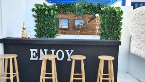 Zona de bar con mostrador de madera, tres taburetes y un cartel que dice 'ENJOY'.
