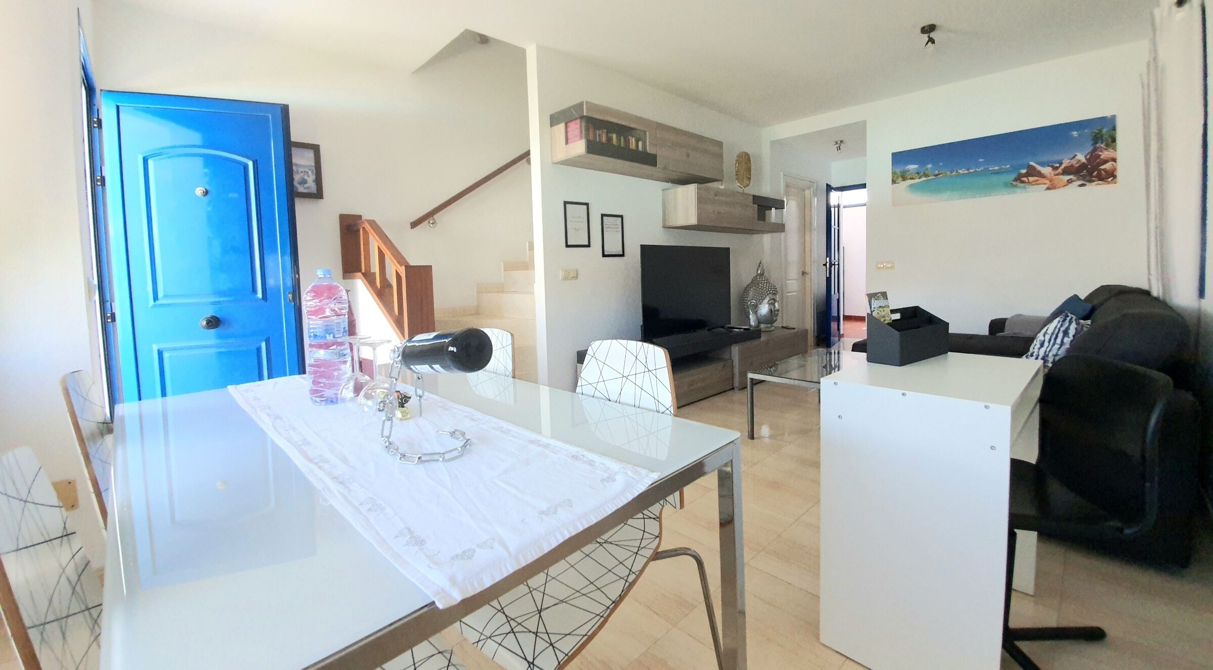 A living room with a sofa, TV, and a dining area with a table and chairs.