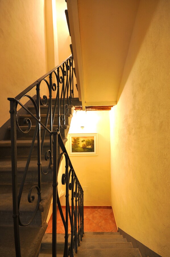 A staircase with ornate black metal railings and a picture on the wall.
