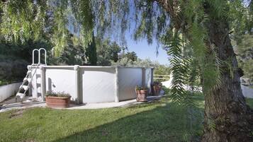 Enjoy a refreshing swim in the pool surrounded by lush greenery and a well-manicured lawn.