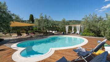 Relax by the serene pool surrounded by lush greenery and comfortable sunbeds.