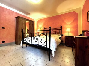 Une chambre à coucher avec un lit à baldaquin, une armoire en bois, une table de chevet avec une lampe et une horloge murale.