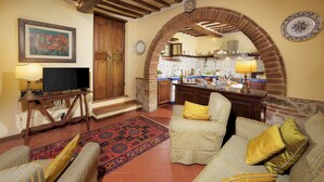 Un salon confortable avec une télévision, un canapé et un tapis à motifs.