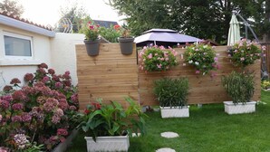 Un jardín con cerca de madera, plantas en macetas y un pérgola.