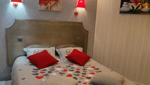 Una cama bien hecha con una colcha estampada, dos almohadas rojas y un cabecero.