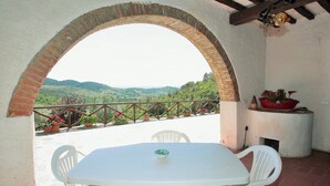 A patio with a white table and chairs, a brick archway, and a view of green hills. - Farmhouse in the hills with panoramic view and swimming pool (Ristonchia)