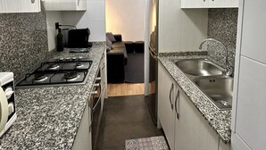 A narrow kitchen with granite countertops, stainless steel appliances, and a small seating area in the background. - Parking available. Pets accepted. Subway nearby. Near the Sagrada Familia (Barcelona)