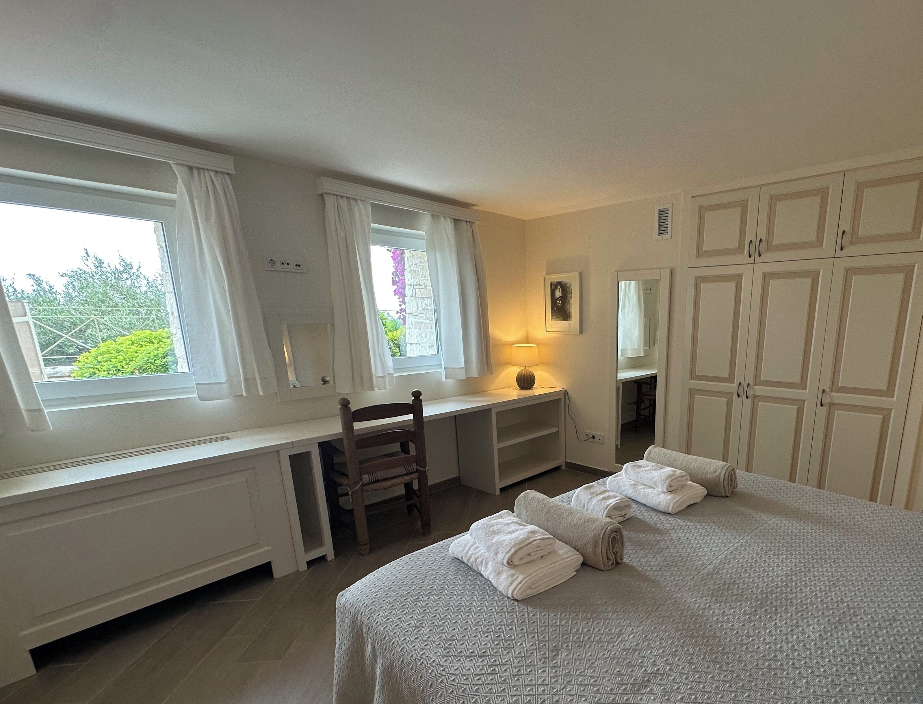 Ein Schlafzimmer mit einem Bett, einem Schreibtisch, einem Stuhl und einem Kleiderschrank.
