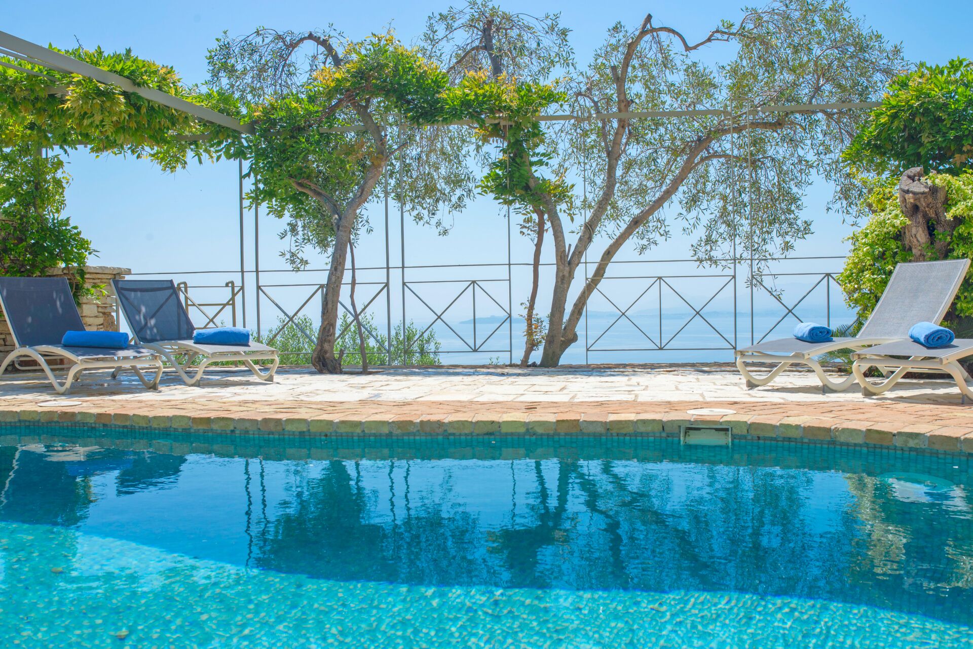 Zona junto a la piscina con sillones de descanso y vista al mar.