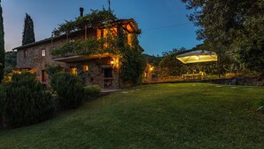 Ein Steinhaus mit gepflegtem Rasen und einer Sitzgelegenheit im Freien.