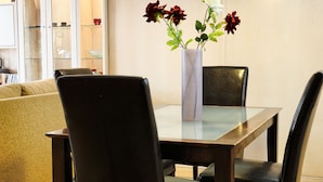 Un comedor con una mesa, sillas y un florero con flores.