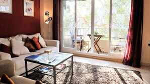 Un salón con sofá, mesa de centro y vistas al exterior a través de un ventanal corredero.