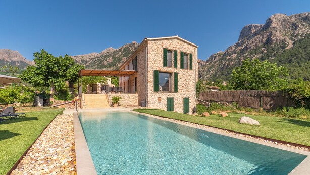 A stone building with a pool, surrounded by a well-maintained lawn and mountains in the background. - CAN SIVELLA GROC - Lovely mediterranean villa with mountain views & stylish pool (Sóller)