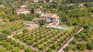 An aerial view of a residential area with a large house featuring a swimming pool, surrounded by lush greenery and smaller buildings. - CAN SIVELLA GROC - Lovely mediterranean villa with mountain views & stylish pool (Sóller)