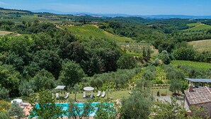 Una villa con piscina, mobiliario exterior y vistas a viñedos.