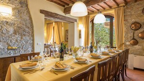 Una larga mesa de comedor dispuesta para una comida en una habitación rústica con paredes de piedra y vigas de madera.