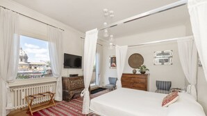 Une chambre avec un grand lit, une télévision, une commode en bois et une vue sur le paysage urbain.