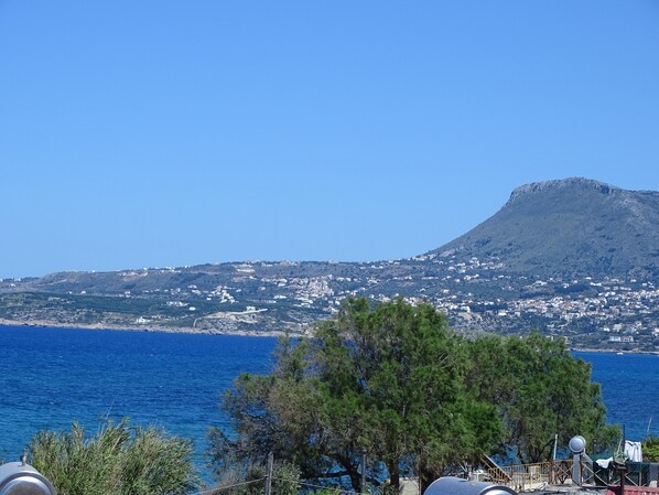 Une vue sur la côte, avec une montagne en arrière-plan et un ciel bleu dégagé.
