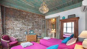 Ein Zimmer mit zwei Betten, einem hölzernen Schminktisch, einem Stuhl und einer Ziegelwand.