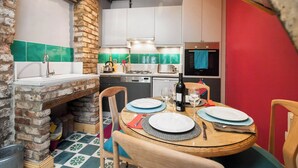 Eine gemütliche Küche mit Backsteinwand, einem Holzespeisetisch für zwei Personen und modernen Geräten.