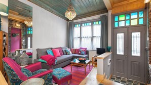 Ein gemütliches Wohnzimmer mit einer Couch, Sesseln, einem Couchtisch und einem Fernseher.