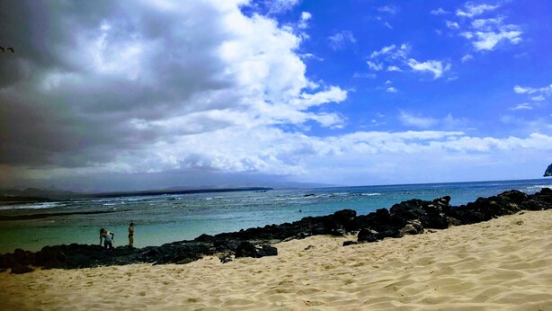 Een strand met heldere lucht en rustig water.