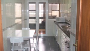 A compact kitchen with a dining area, white cabinets, a microwave, and a sink. - Large three bedroom by the seaside promenade (Funchal)