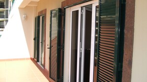 A row of closed doors with shutters, a tiled floor, and a balcony with a railing. - Large three bedroom by the seaside promenade (Funchal)